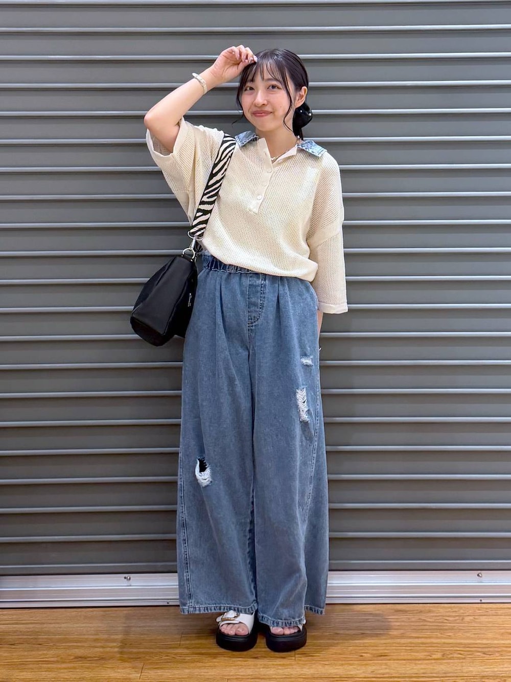 ブルー系のデニムパンツ、ホワイト系のサンダル、ブラック系のショルダーバッグを着用したレディースの夏コーディネートの1枚目の写真