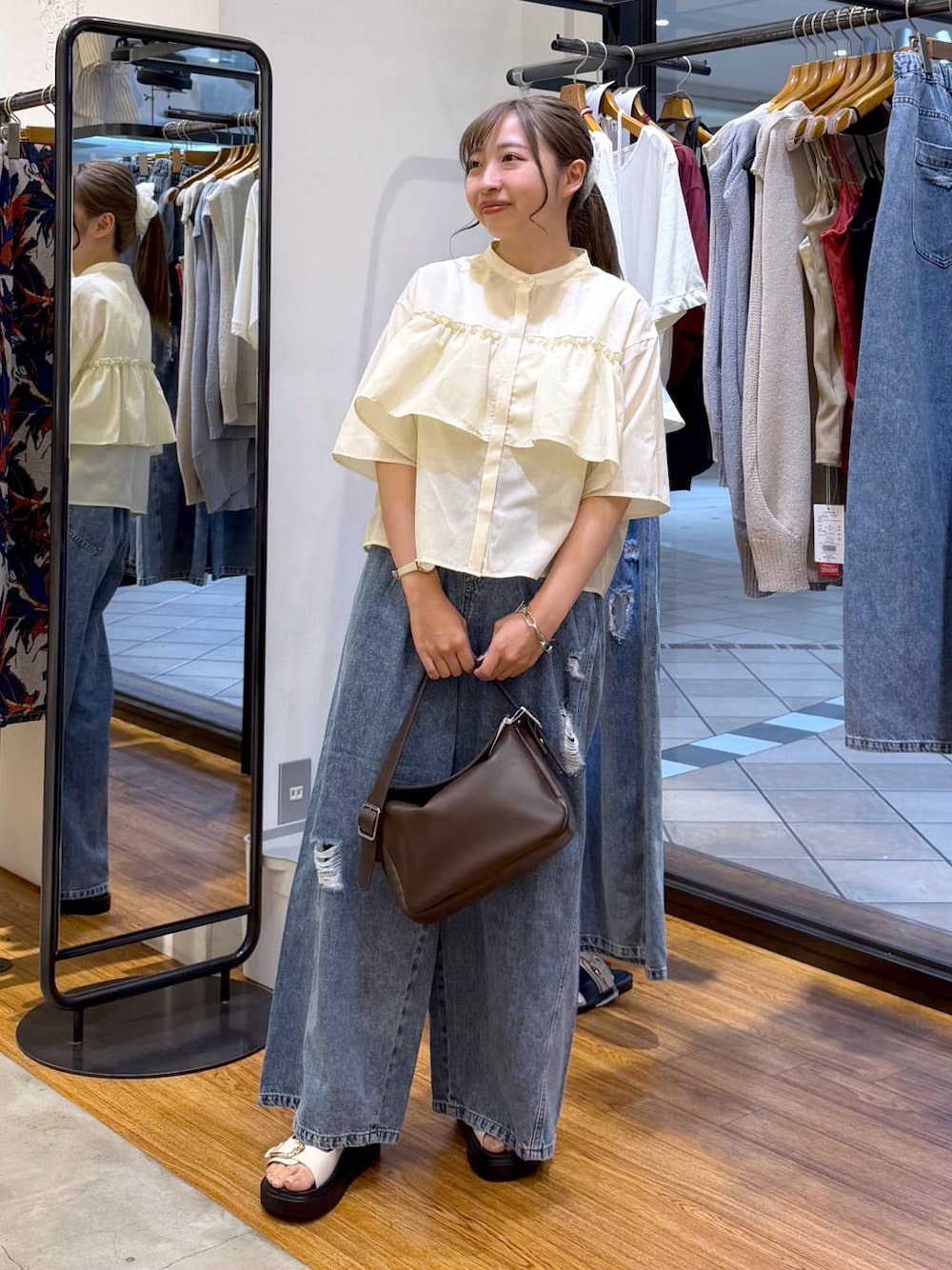 ブルー系のデニムパンツ、ホワイト系のサンダル、ブラウン系のショルダーバッグを着用したレディースの夏コーディネートの1枚目の写真