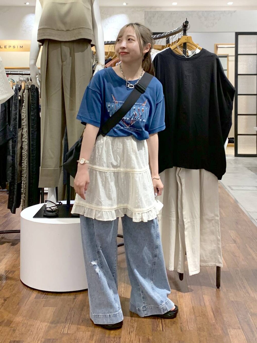 ブルー系のデニムパンツ、ブラック系のサンダル、ブラック系のショルダーバッグを着用したレディースの夏コーディネートの1枚目の写真