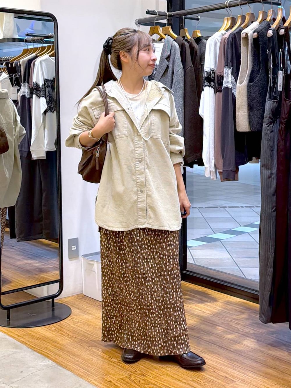 ブラウン系のボストンバッグ、ブラウン系のローファー、ホワイト系のTシャツ/カットソーを着用したレディースの秋コーディネートの1枚目の写真