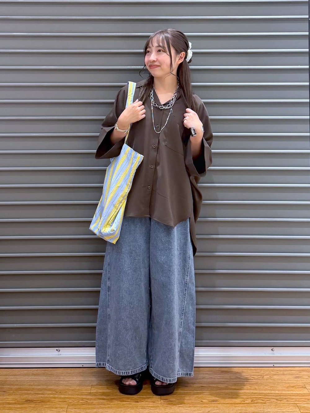 ブルー系のトートバッグ、ブラウン系のシャツ/ブラウス、ブラック系のサンダルを着用したレディースの夏コーディネートの1枚目の写真
