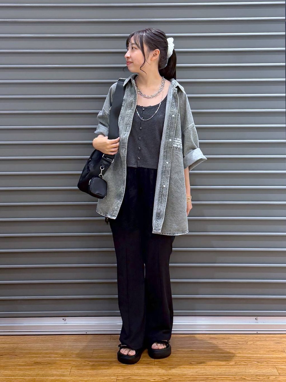 ブラック系のショルダーバッグ、グレー系のTシャツ/カットソー、ブラック系のサンダルを着用したレディースの夏コーディネートの1枚目の写真