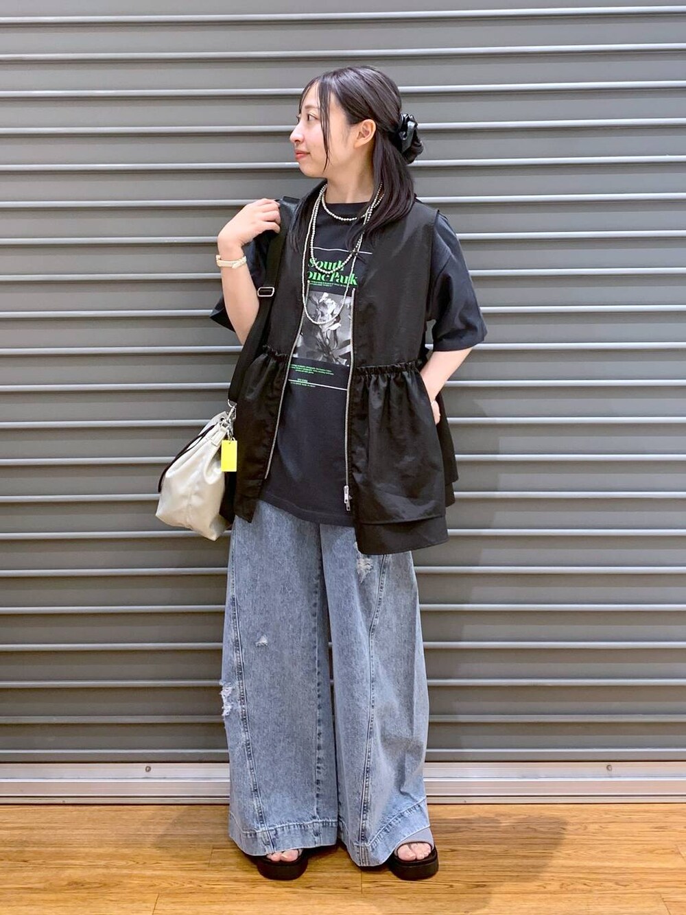 シルバー系のサンダル、ブルー系のデニムパンツ、ブラック系のベストを着用したレディースの夏コーディネートの1枚目の写真