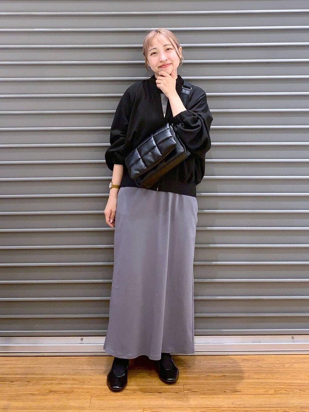 ブラック系のショルダーバッグ、ブラック系のパンプス、グレー系のスカートを着用したレディースの春コーディネートの1枚目の写真