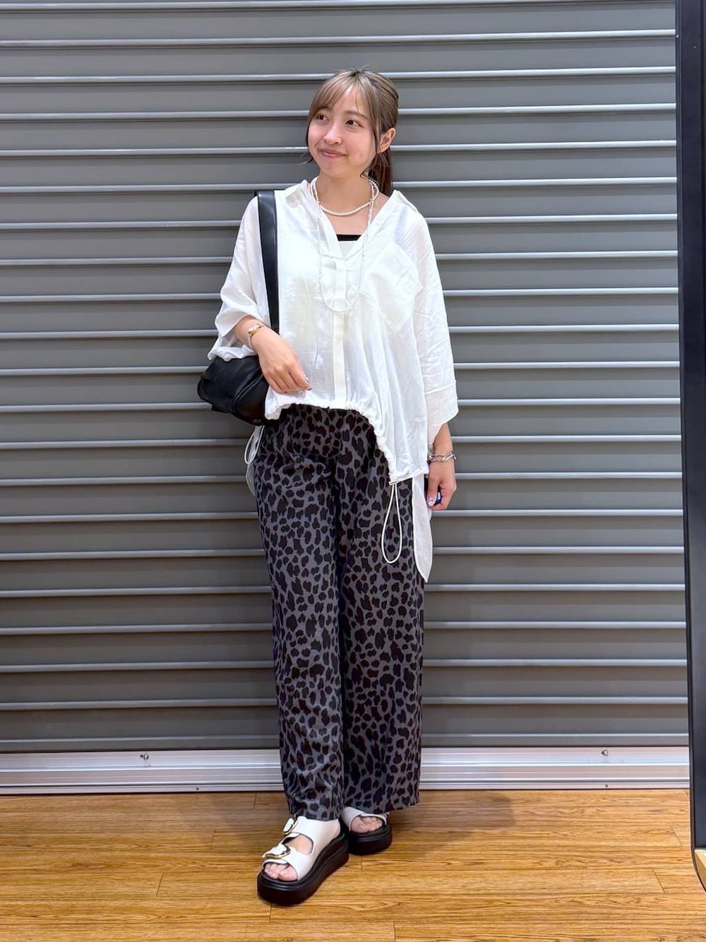ホワイト系のシャツ/ブラウス、グレー系のその他パンツ、ブラック系のショルダーバッグを着用したレディースの夏コーディネートの1枚目の写真