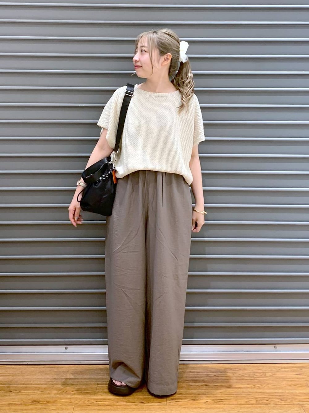 ホワイト系のニット/セーター、ブラウン系のサンダル、ブラック系のショルダーバッグを着用したレディースの夏コーディネートの1枚目の写真