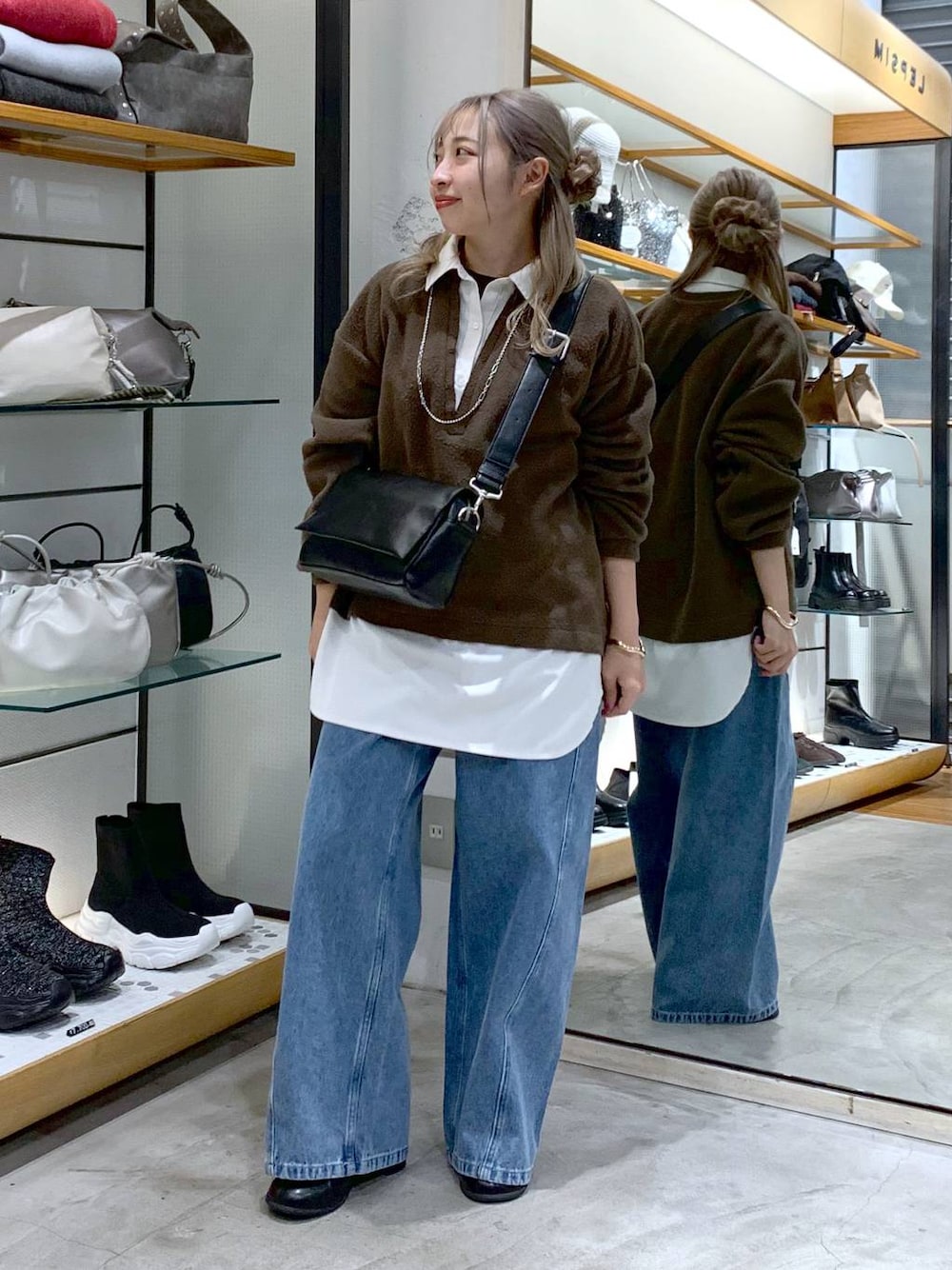 ブラック系のショルダーバッグ、ブラック系のブーツ、ブルー系のデニムパンツを着用したレディースの冬コーディネートの1枚目の写真