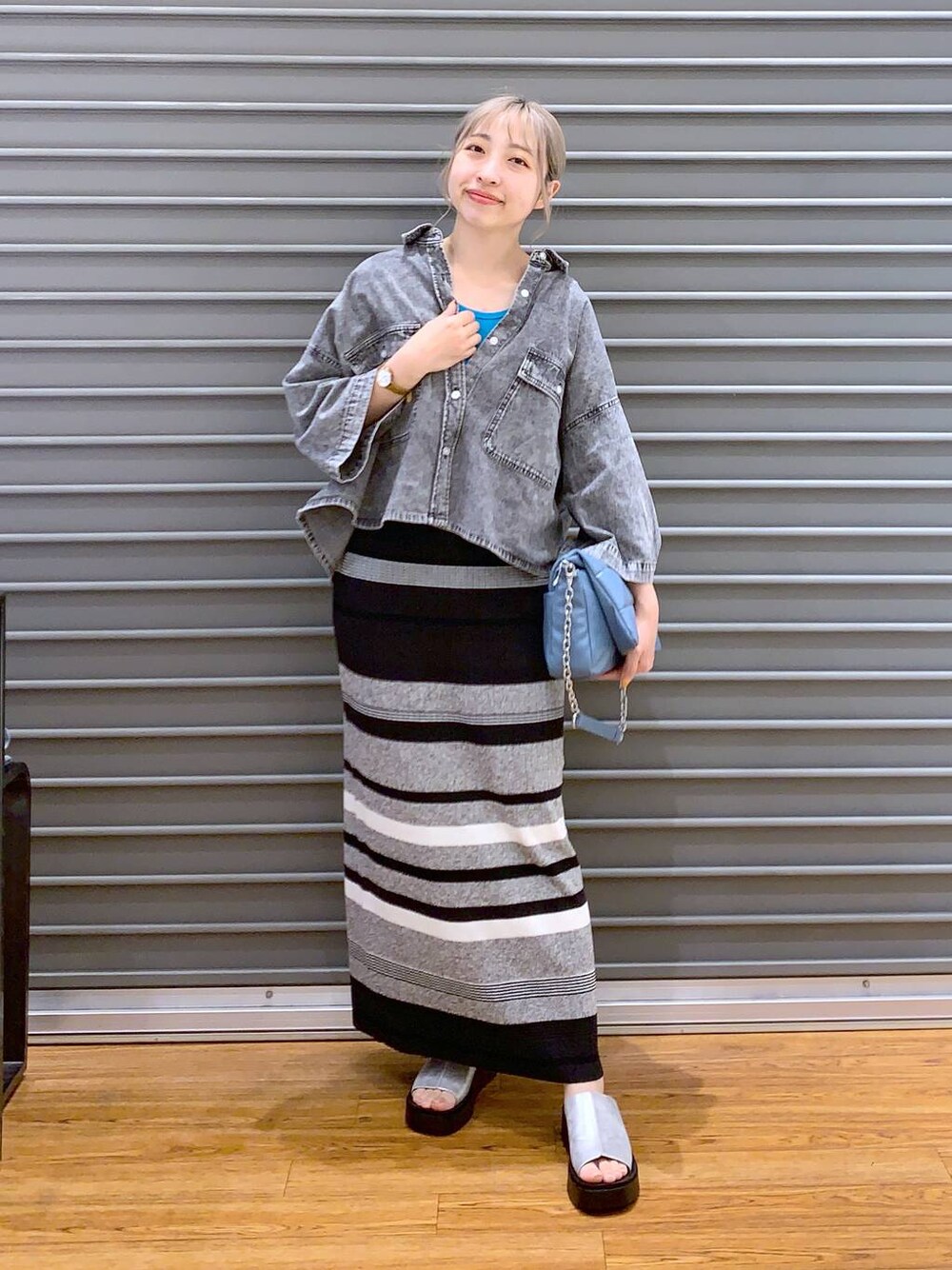ブルー系のショルダーバッグ、ブラック系のシャツ/ブラウス、グレー系のサンダルを着用したレディースの春コーディネートの1枚目の写真