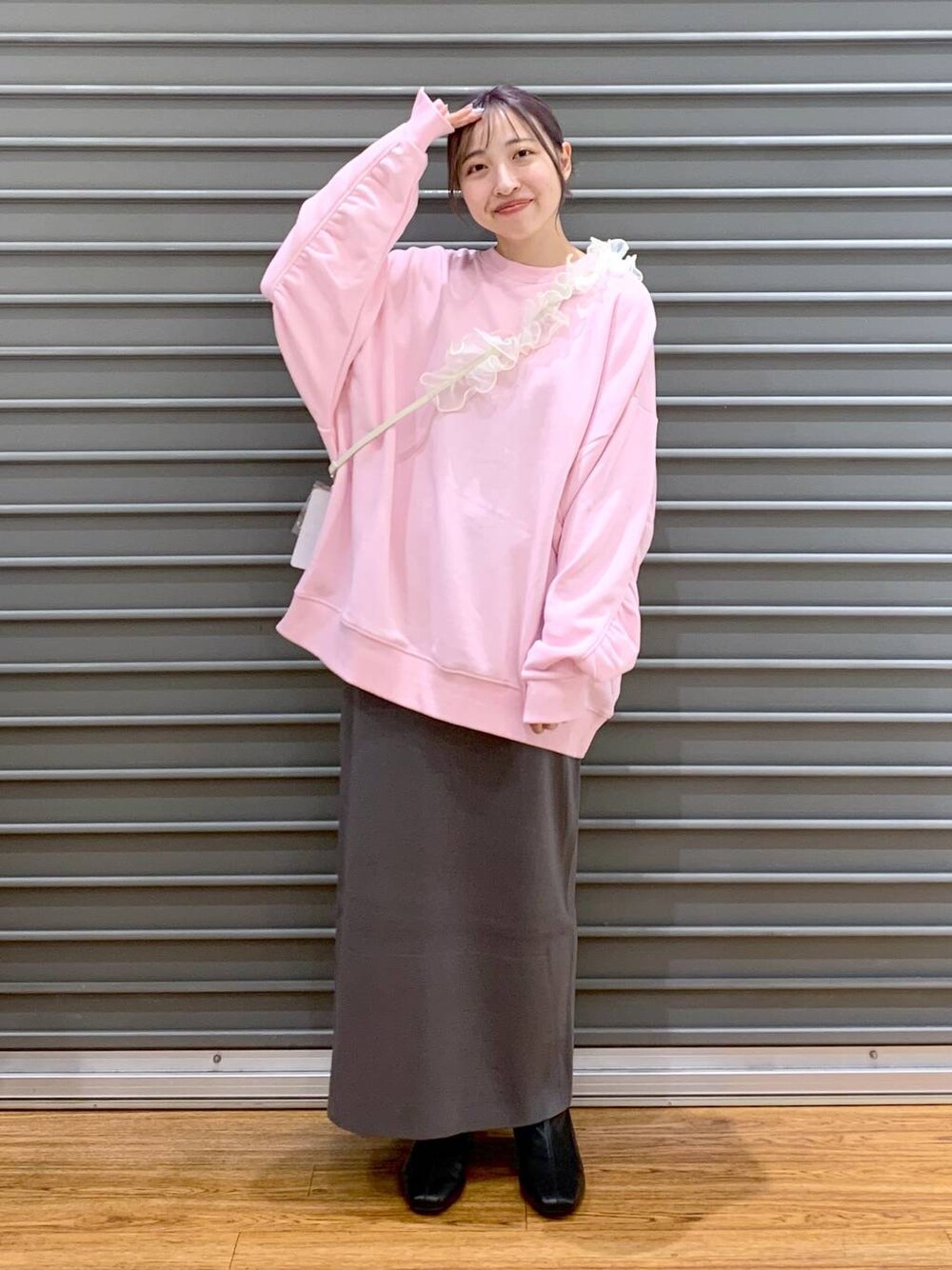 グレー系のスカート、ブラック系のブーツ、ピンク系のスウェットを着用したレディースの冬コーディネートの1枚目の写真