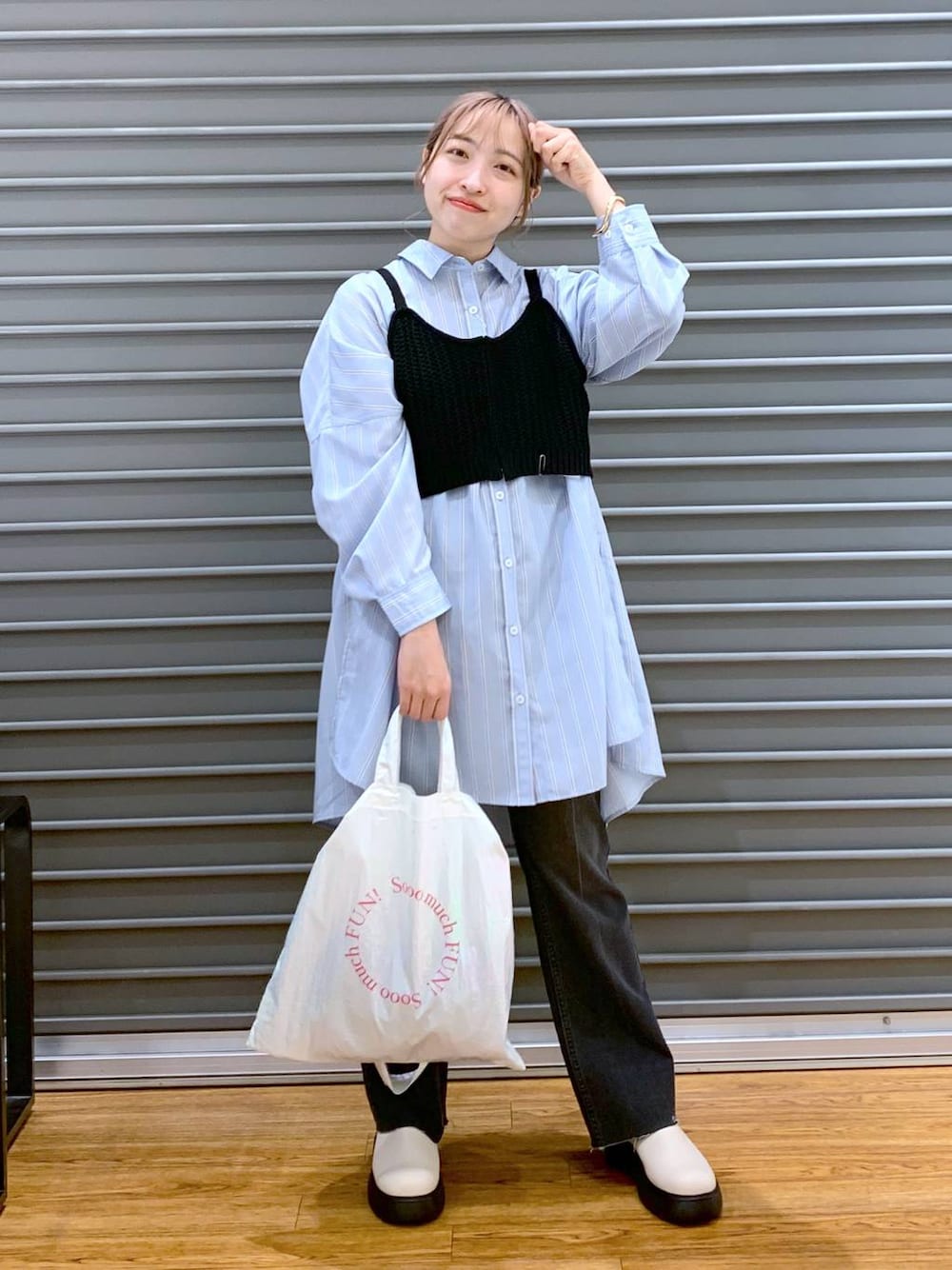 ブラック系のニット/セーター、ブルー系のチュニック、ホワイト系のトートバッグを着用したレディースの春コーディネートの1枚目の写真