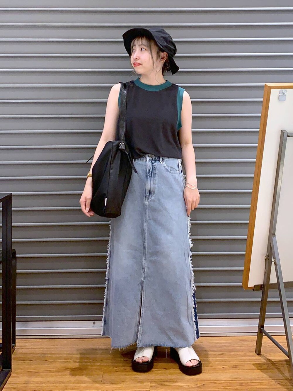 グレー系のタンクトップ、ホワイト系のサンダル、ブラック系のショルダーバッグを着用したレディースの夏コーディネートの1枚目の写真