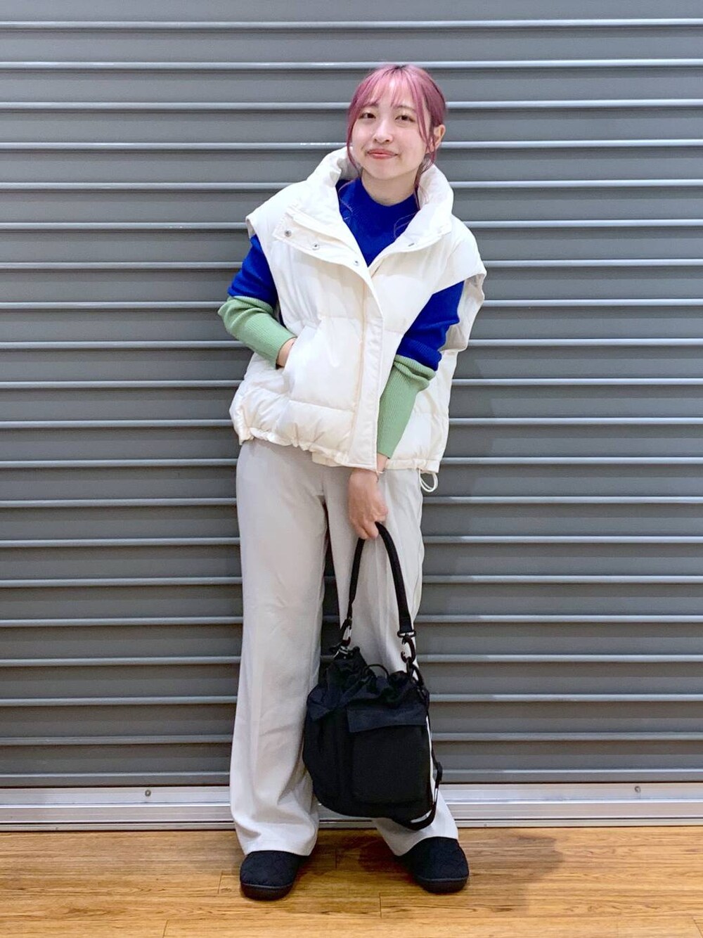 ブラック系のショルダーバッグ、ブルー系のニット/セーター、ホワイト系のダウンベストを着用したレディースの秋コーディネートの1枚目の写真