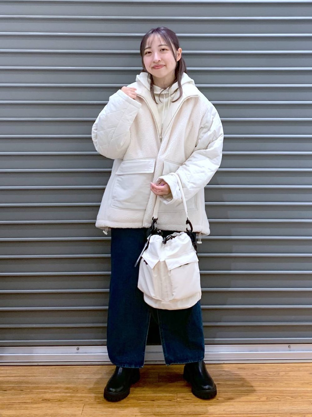 ホワイト系のショルダーバッグ、ブルー系のジャンパースカート、ブラック系のブーツを着用したレディースの冬コーディネートの1枚目の写真