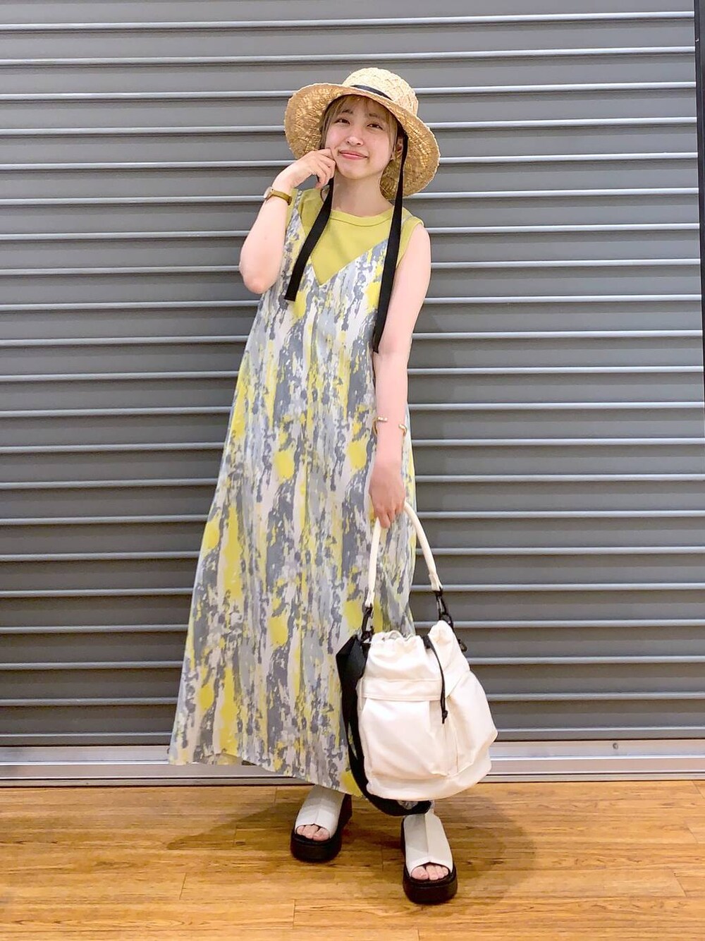 イエロー系のワンピース、イエロー系のタンクトップ、ホワイト系のショルダーバッグを着用したレディースの春コーディネートの1枚目の写真