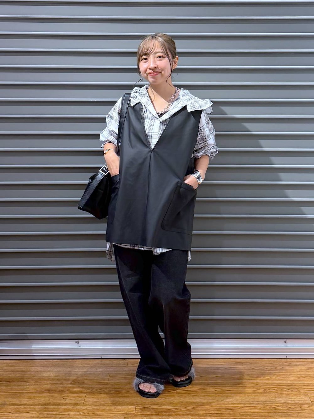 ブラック系のベスト、グレー系のサンダル、ブラック系のデニムパンツを着用したレディースの夏コーディネートの1枚目の写真