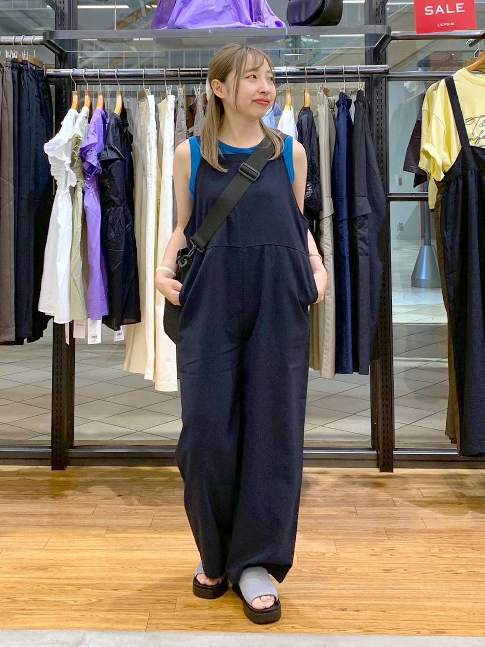 ブルー系のタンクトップ、シルバー系のサンダル、ブラック系のショルダーバッグを着用したレディースの秋コーディネートの1枚目の写真