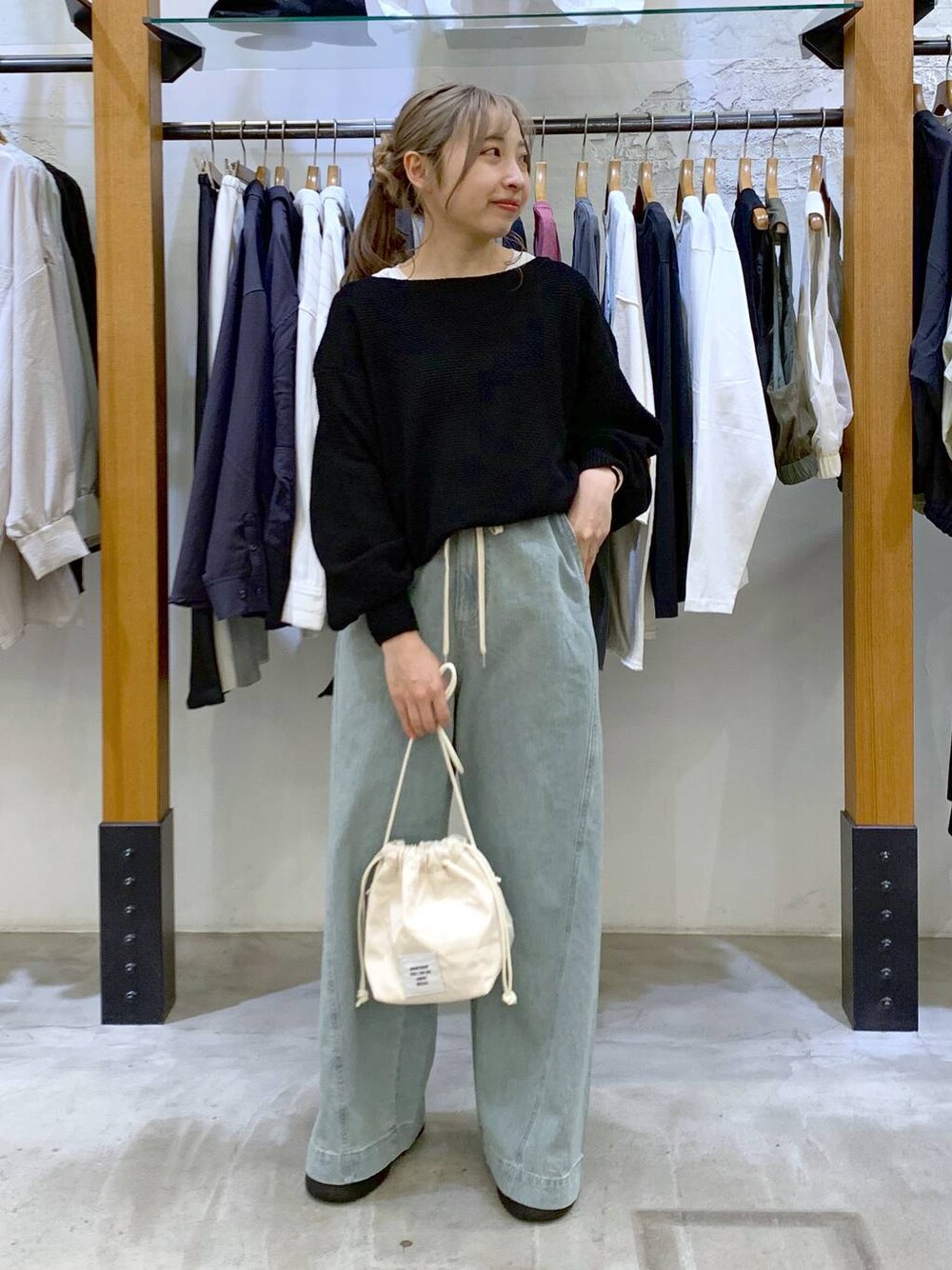 ブラック系のニット/セーター、ホワイト系のショルダーバッグ、ブルー系のデニムパンツを着用したレディースの春コーディネートの1枚目の写真