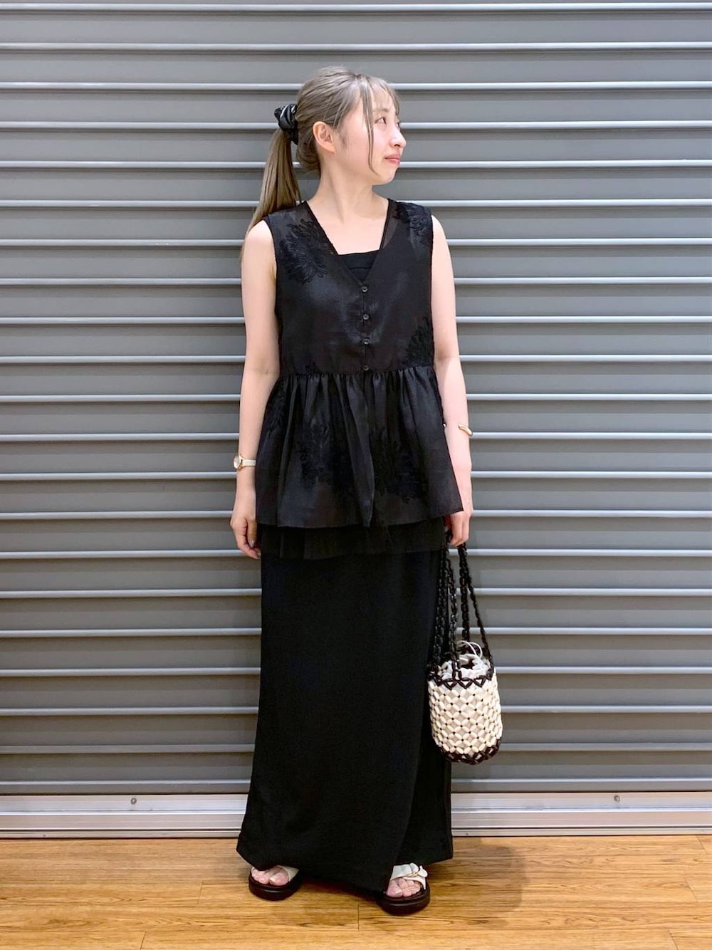 ホワイト系のサンダル、ホワイト系のハンドバッグ、ブラック系のシャツ/ブラウスを着用したレディースの夏コーディネートの1枚目の写真