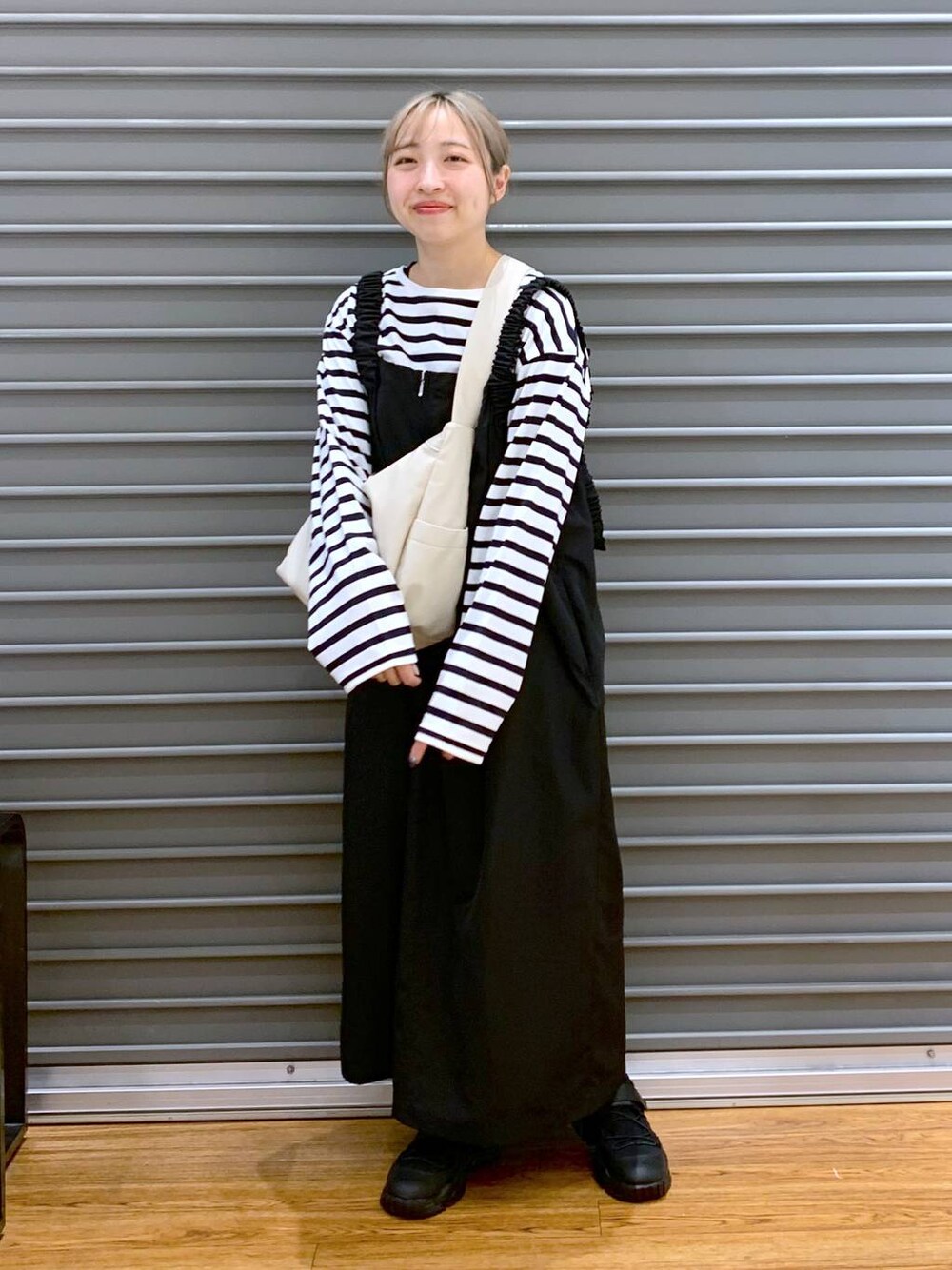ブルー系のTシャツ/カットソー、ブラック系のスニーカー、ブラック系のジャンパースカートを着用したレディースの冬コーディネートの1枚目の写真