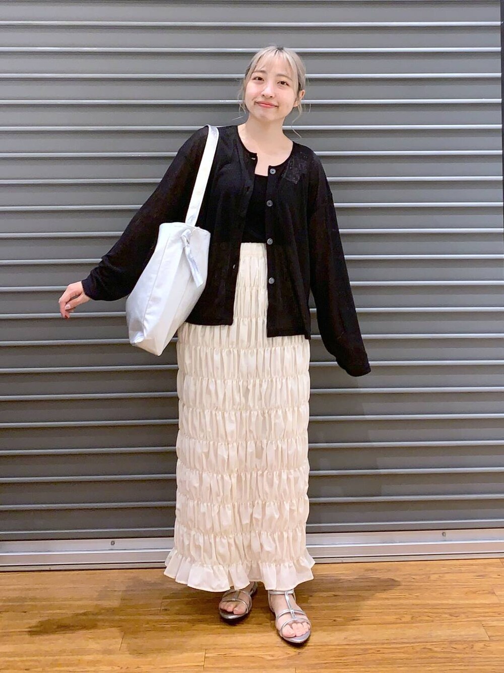 シルバー系のサンダル、ブラック系のカーディガン/ボレロ、グレー系のショルダーバッグを着用したレディースの夏コーディネートの1枚目の写真