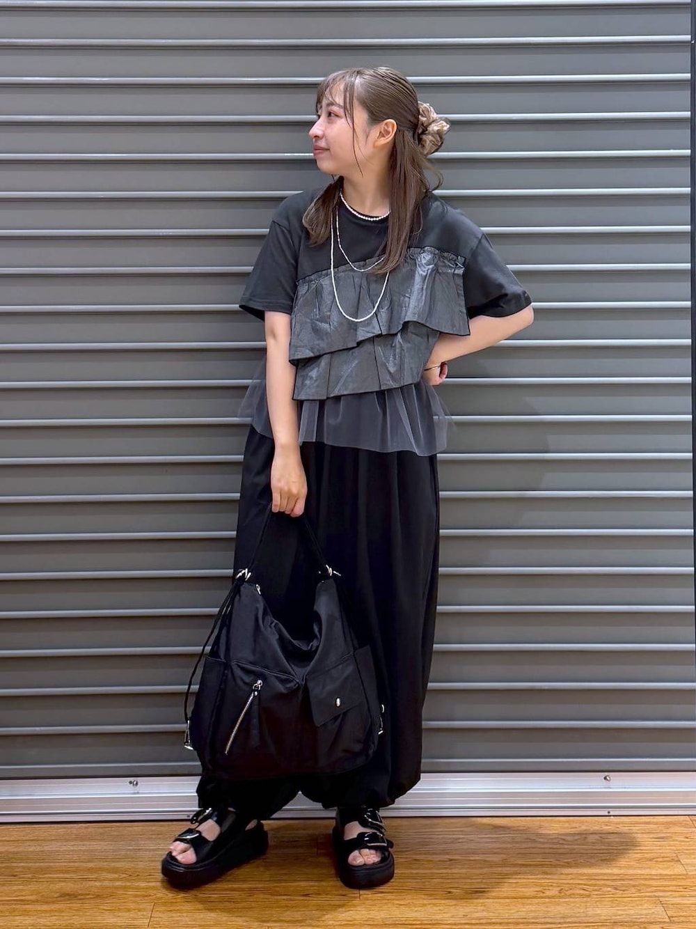 ブラック系のショルダーバッグ、ブラック系のサンダル、グレー系のTシャツ/カットソーを着用したレディースの夏コーディネートの1枚目の写真