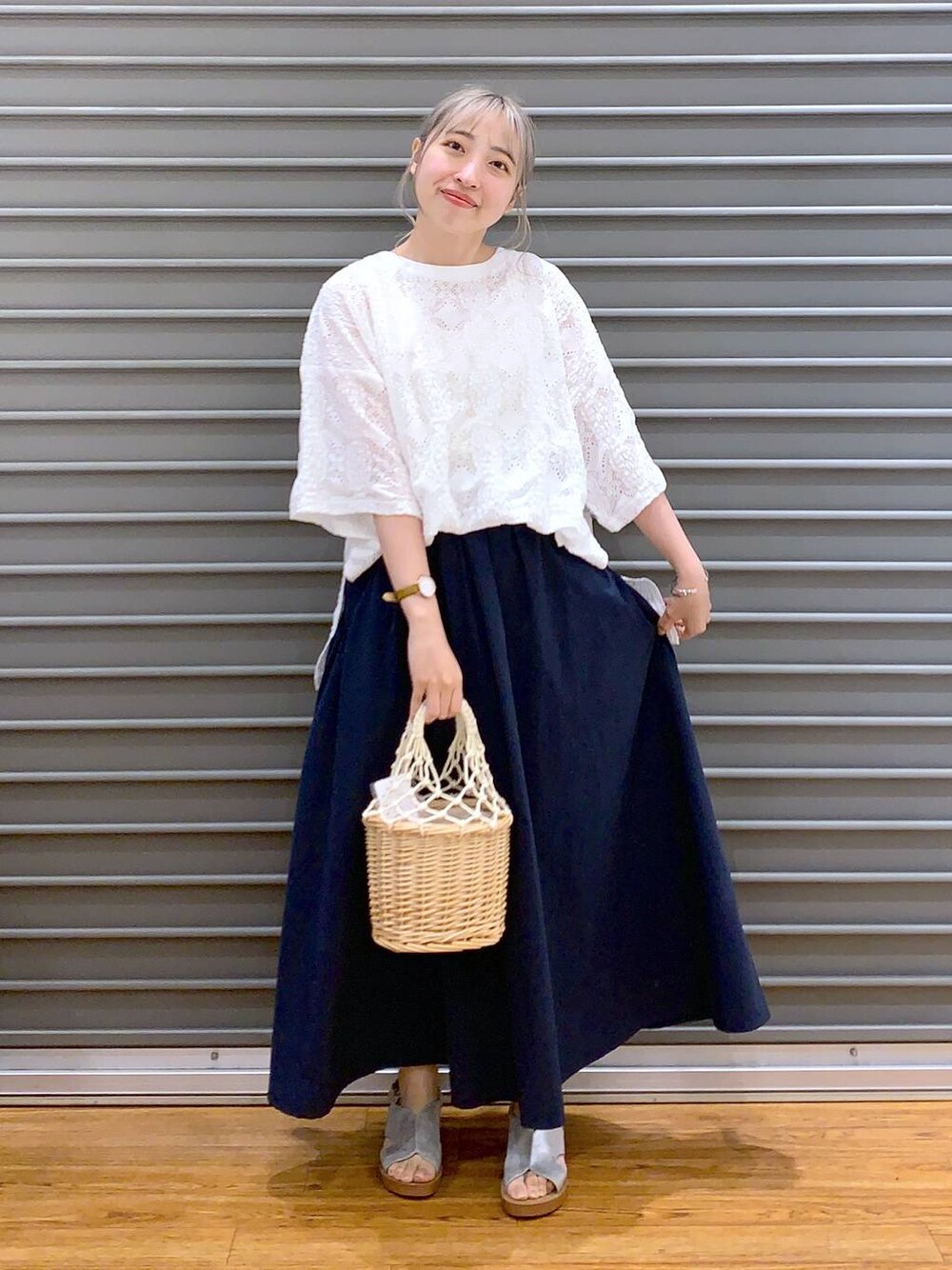 ブルー系のスカート、シルバー系のサンダル、ホワイト系のかごバッグを着用したレディースの夏コーディネートの1枚目の写真