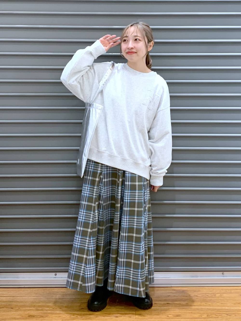 シルバー系のトートバッグ、ブラック系のブーツ、グリーン系のスカートを着用したレディースの冬コーディネートの1枚目の写真