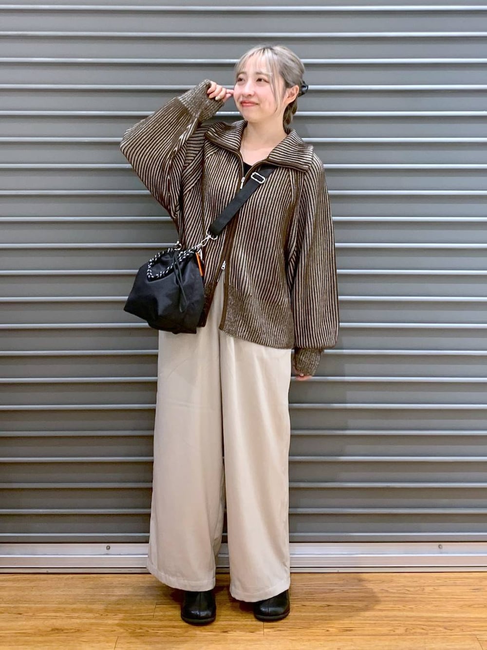 ブラック系のショルダーバッグ、ブラウン系のカーディガン/ボレロ、ブラック系のブーツを着用したレディースの冬コーディネートの1枚目の写真