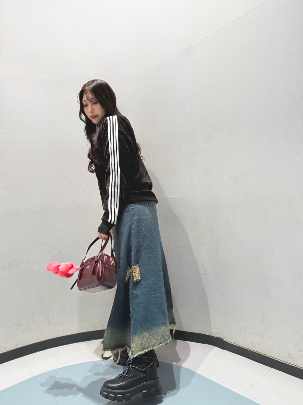 ブラック系のトップス、レッド系のバッグ、ブラック系のブーツを着用したレディースの秋コーディネートの1枚目の写真