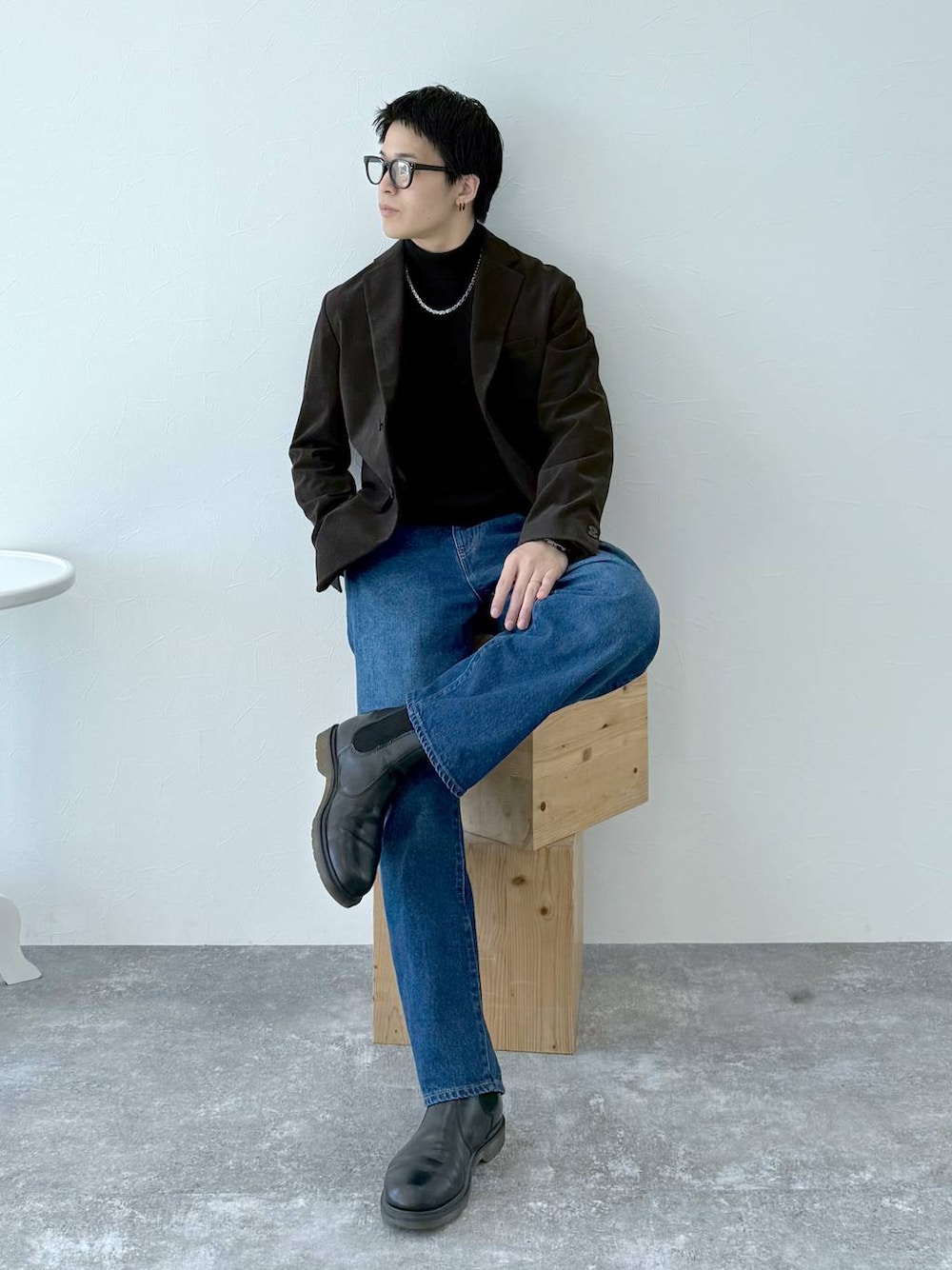 ブラック系のニット/セーター、ブラウン系のテーラードジャケット、ブルー系のデニムパンツを着用したメンズの秋コーディネートの1枚目の写真