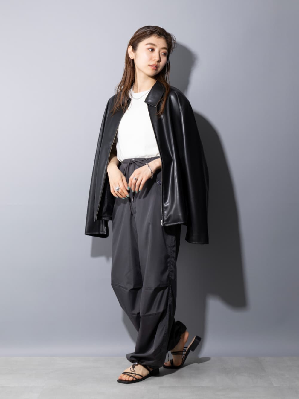 ブラック系のサンダル、ホワイト系のTシャツ/カットソー、ブラック系のライダースジャケットを着用したレディースの春コーディネートの1枚目の写真