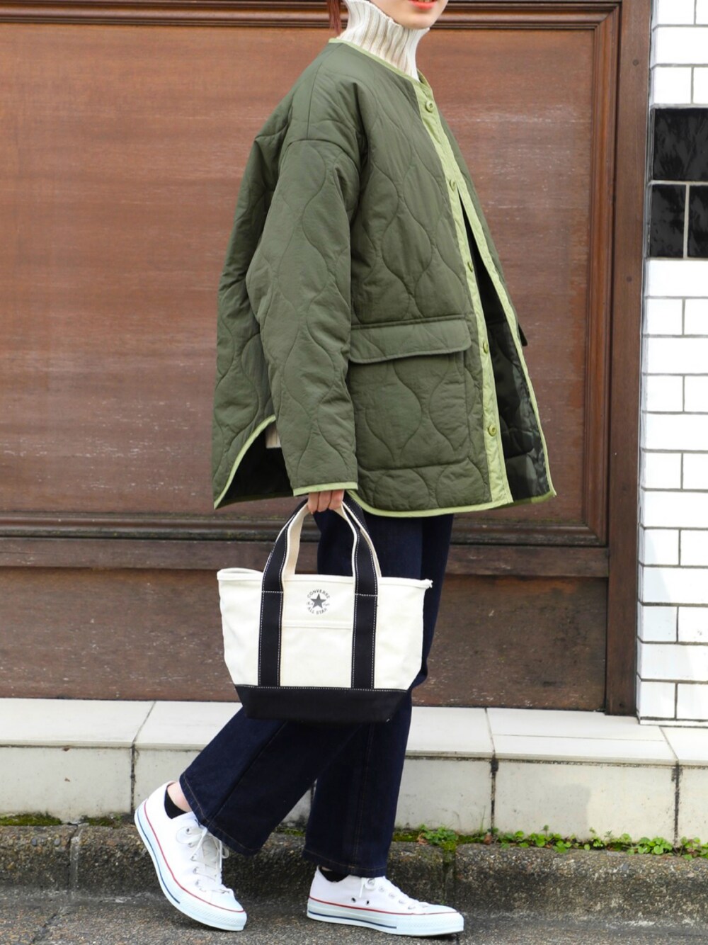 グリーン系のミリタリージャケット、ブルー系のデニムパンツ、ホワイト系のニット/セーターを着用したレディースの秋コーディネートの1枚目の写真