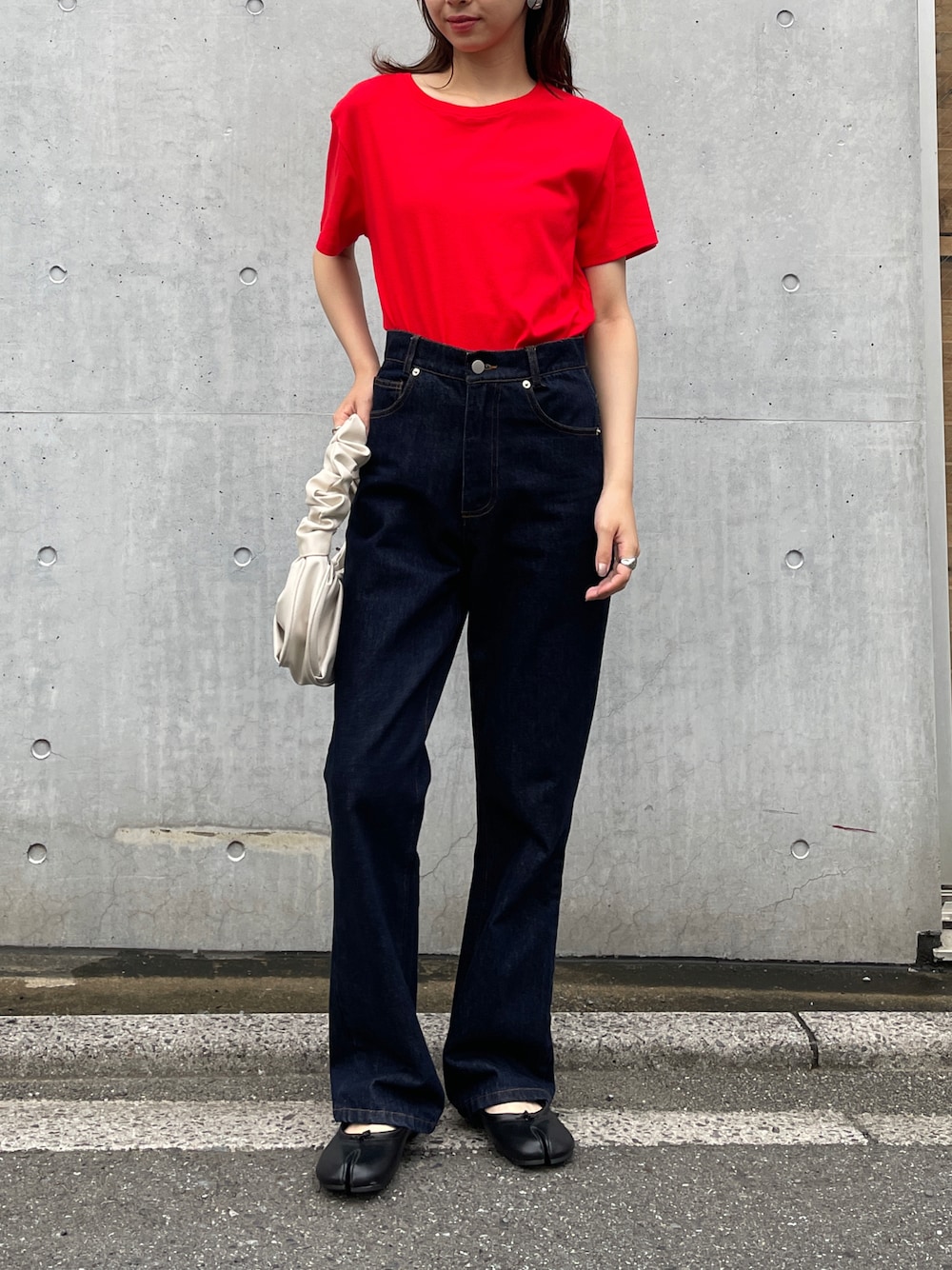ブラック系のパンプス、ホワイト系のハンドバッグ、ブルー系のデニムパンツを着用したレディースの夏コーディネートの1枚目の写真