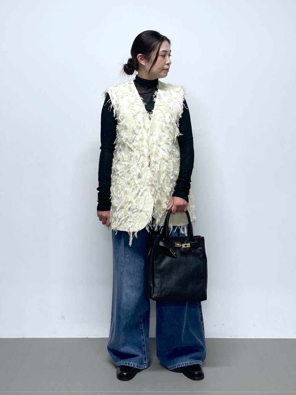 ブルー系のデニムパンツ、ブラック系のTシャツ/カットソー、ホワイト系のベストを着用したレディースの冬コーディネートの1枚目の写真
