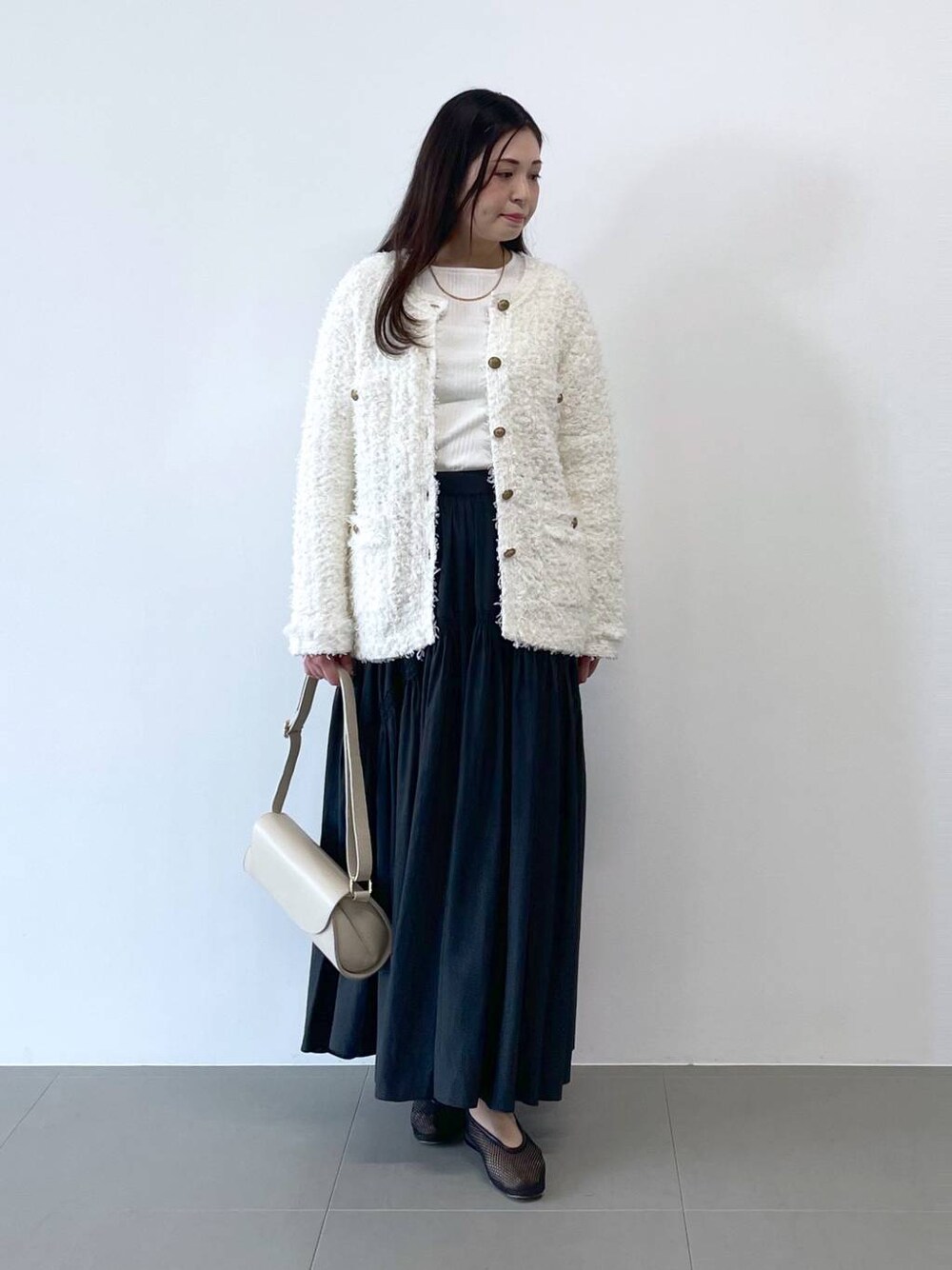 ホワイト系のショルダーバッグ、ホワイト系のカーディガン/ボレロを着用したレディースの冬コーディネートの1枚目の写真