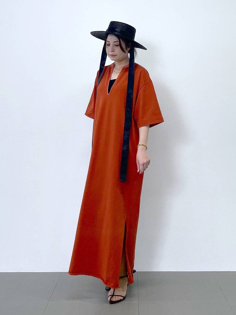 ブラック系のサンダル、オレンジ系のワンピース、ブラウン系のネックレスを着用したレディースの春コーディネートの1枚目の写真