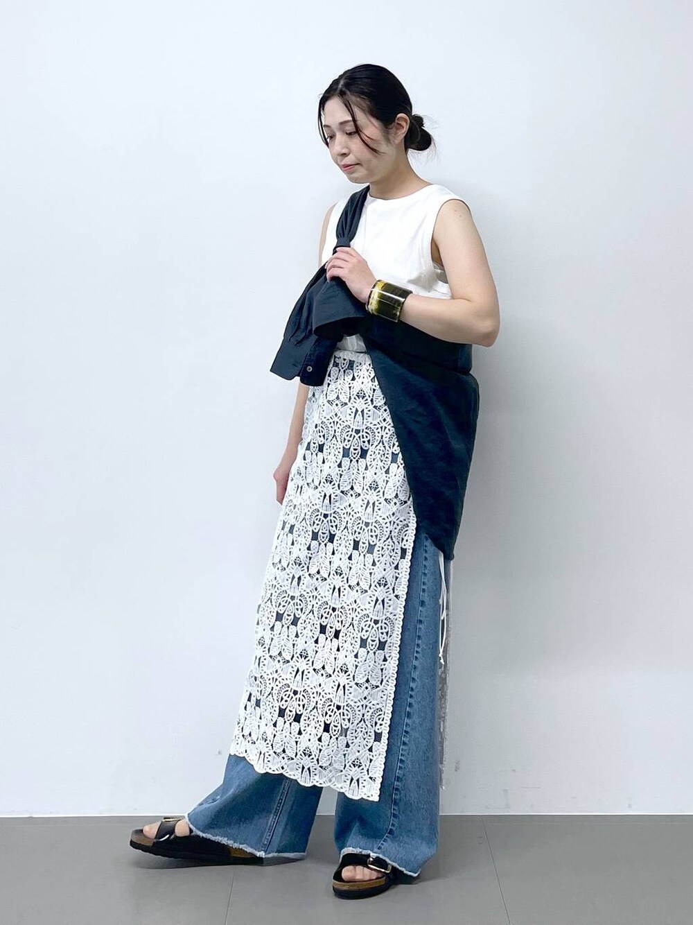 ブルー系のシャツ/ブラウス、ブラック系のサンダル、ブルー系のデニムパンツを着用したレディースの春コーディネートの1枚目の写真