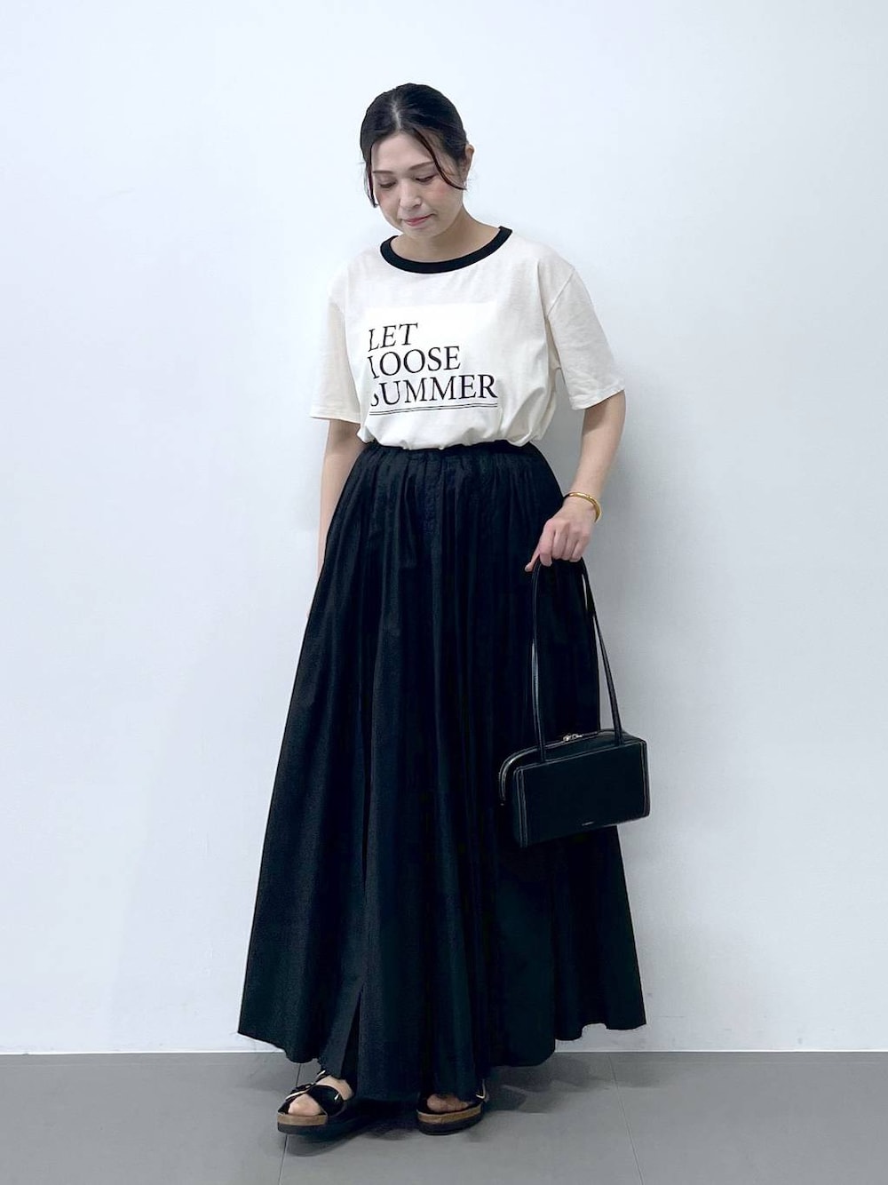 ブラック系のサンダル、ホワイト系のTシャツ/カットソーを着用したレディースの春コーディネートの1枚目の写真