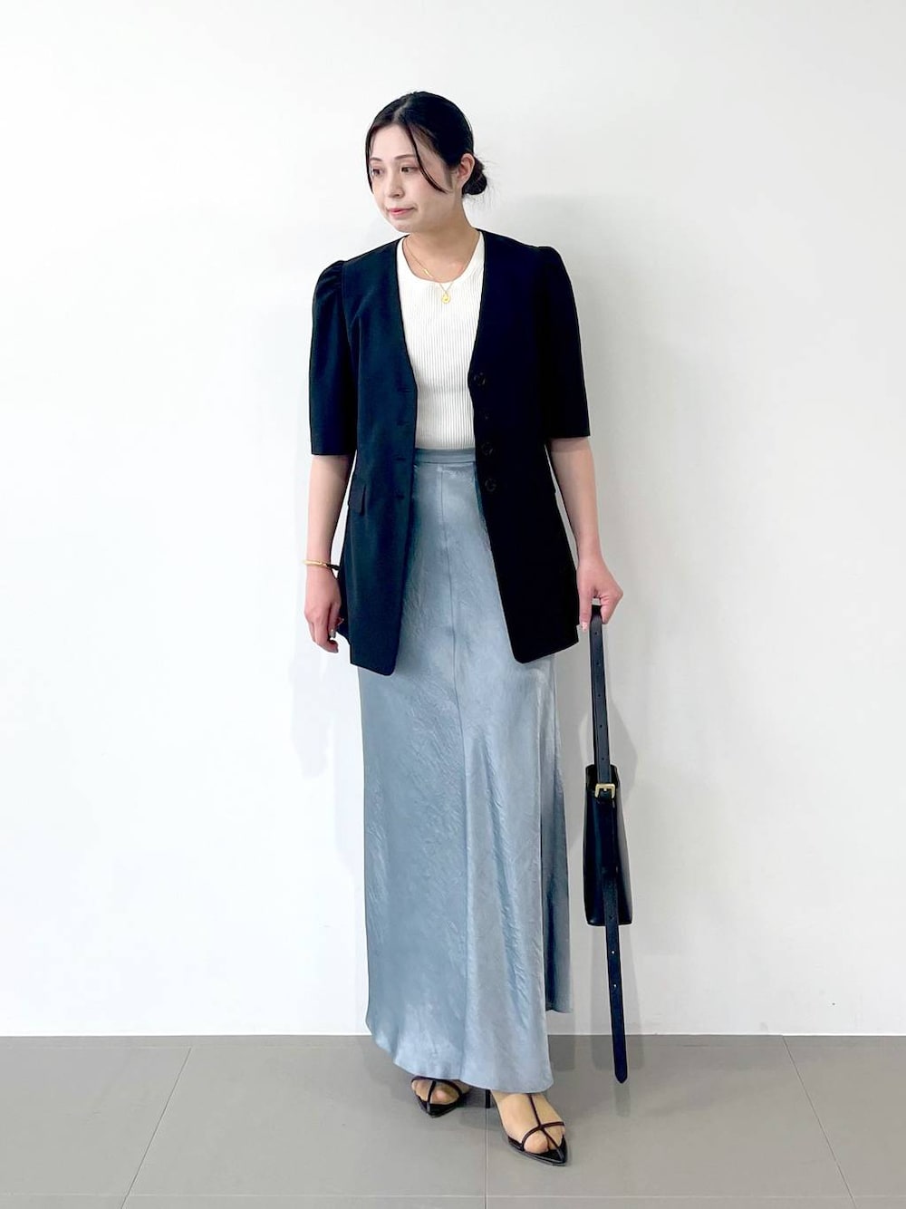 ブラック系のサンダル、ブラック系のショルダーバッグ、ブルー系のスカートを着用したレディースの春コーディネートの1枚目の写真