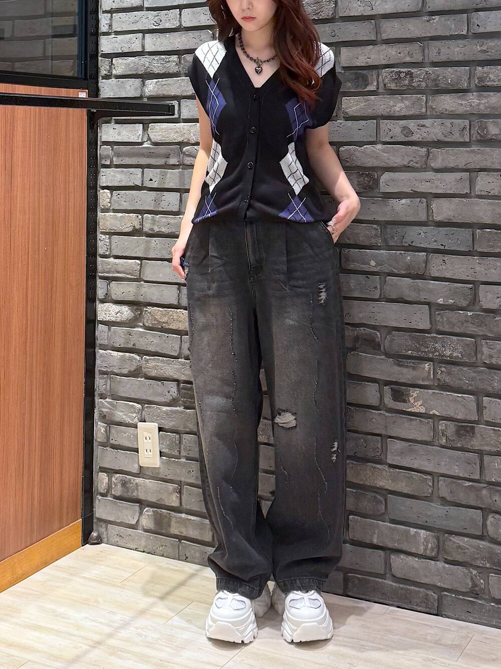 ホワイト系のスニーカー、ブラック系のデニムパンツ、ブラック系のベストを着用したレディースの秋コーディネートの1枚目の写真