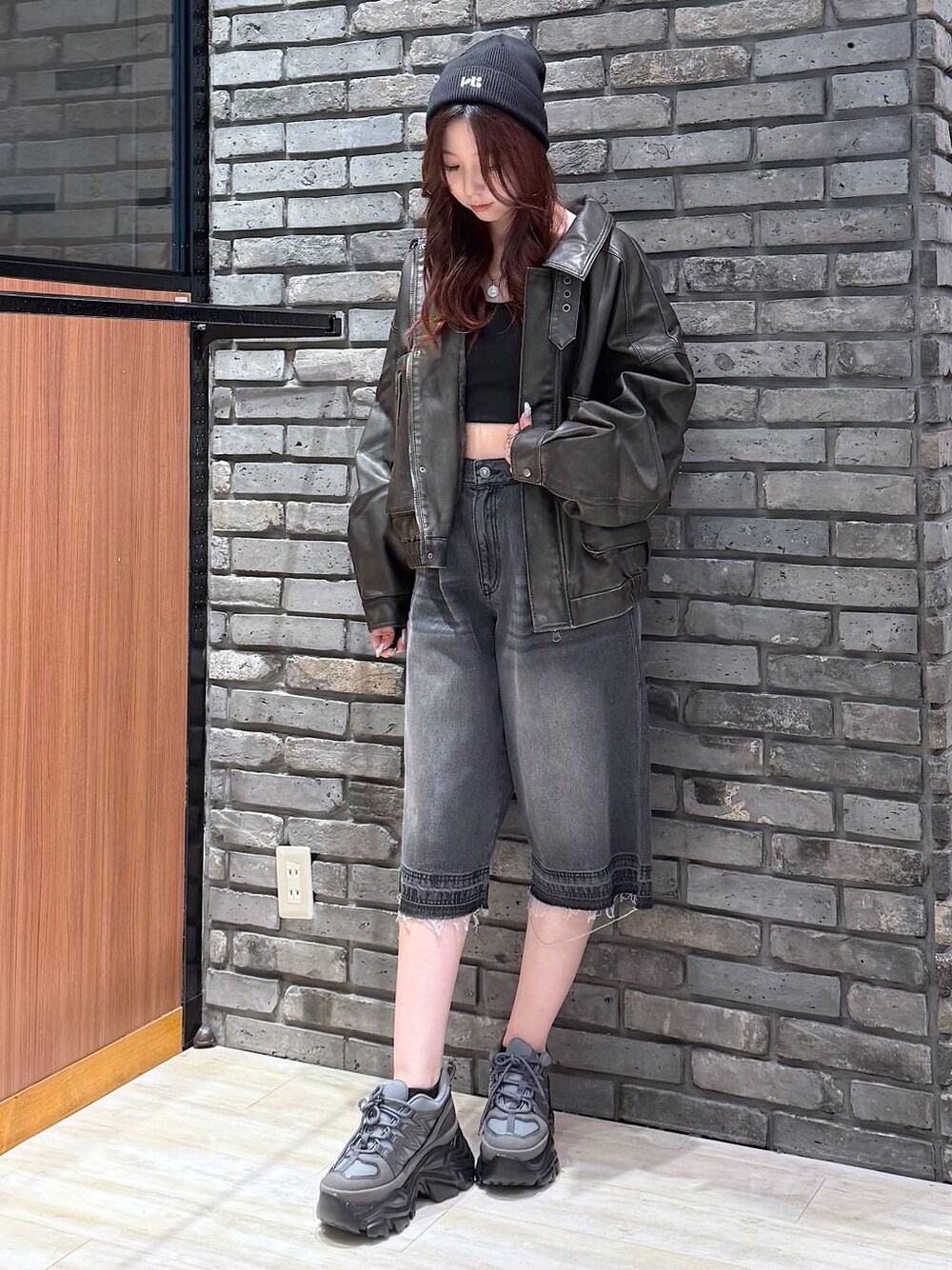 グレー系のスニーカー、ブラック系のデニムパンツ、ブラック系のブルゾンを着用したレディースの秋コーディネートの1枚目の写真
