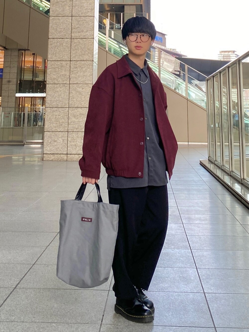 ブラック系のスラックス、ブラック系のドレスシューズ、グレー系のトートバッグを着用したメンズの春コーディネートの1枚目の写真