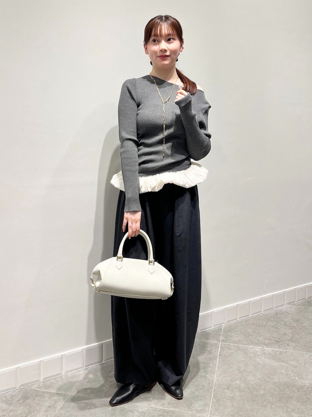 グレー系のその他パンツ、グレー系のニット/セーター、ホワイト系のボストンバッグを着用したレディースの秋コーディネートの1枚目の写真
