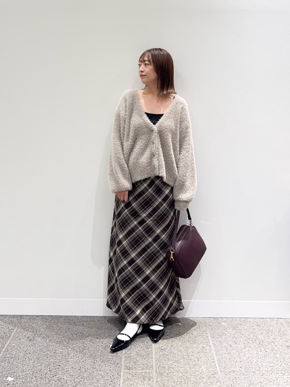 ベージュ系のカーディガン/ボレロ、ブラウン系のスカート、レッド系のショルダーバッグを着用したレディースの秋コーディネートの1枚目の写真