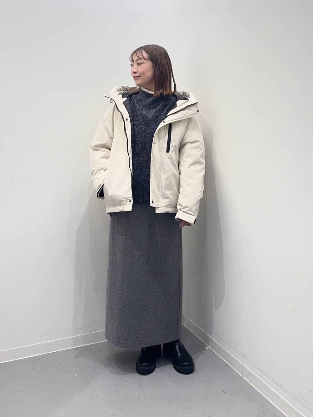 ホワイト系のダウンジャケット/コート、グレー系のニット/セーター、グレー系のスカートを着用したレディースの冬コーディネートの1枚目の写真