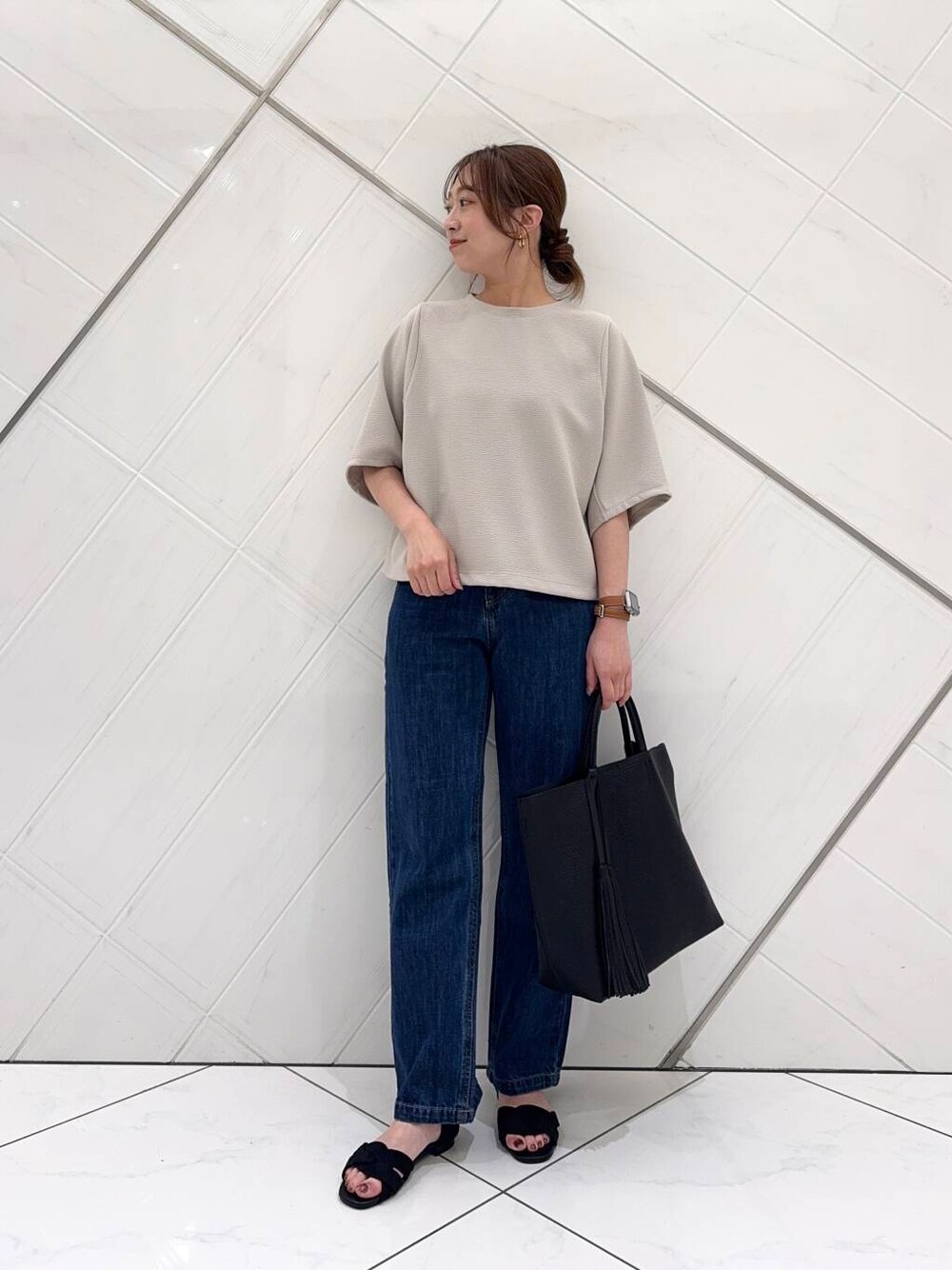 ブルー系のデニムパンツ、ブラック系のトートバッグ、ブラック系のサンダルを着用したレディースの春コーディネートの1枚目の写真