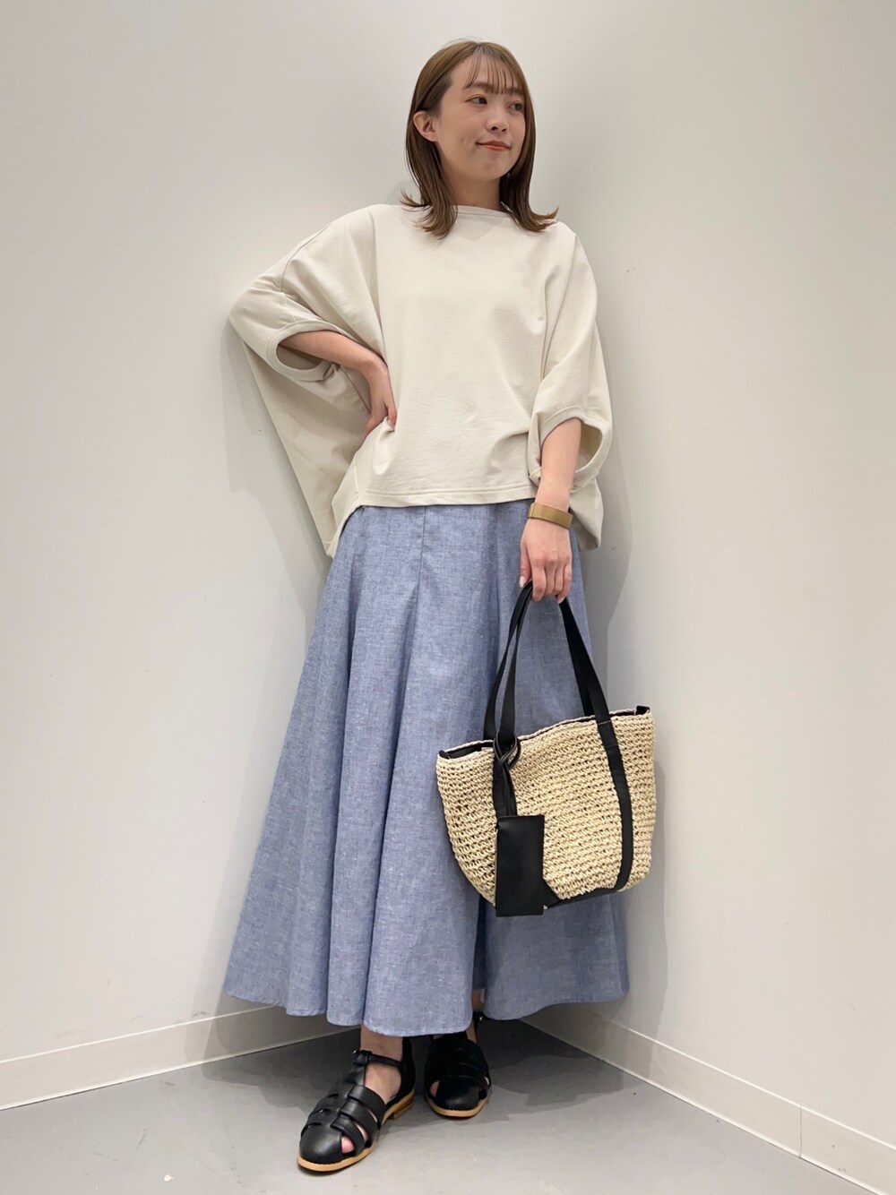 ベージュ系のTシャツ/カットソー、ブルー系のスカート、ブラック系のサンダルを着用したレディースの春コーディネートの1枚目の写真