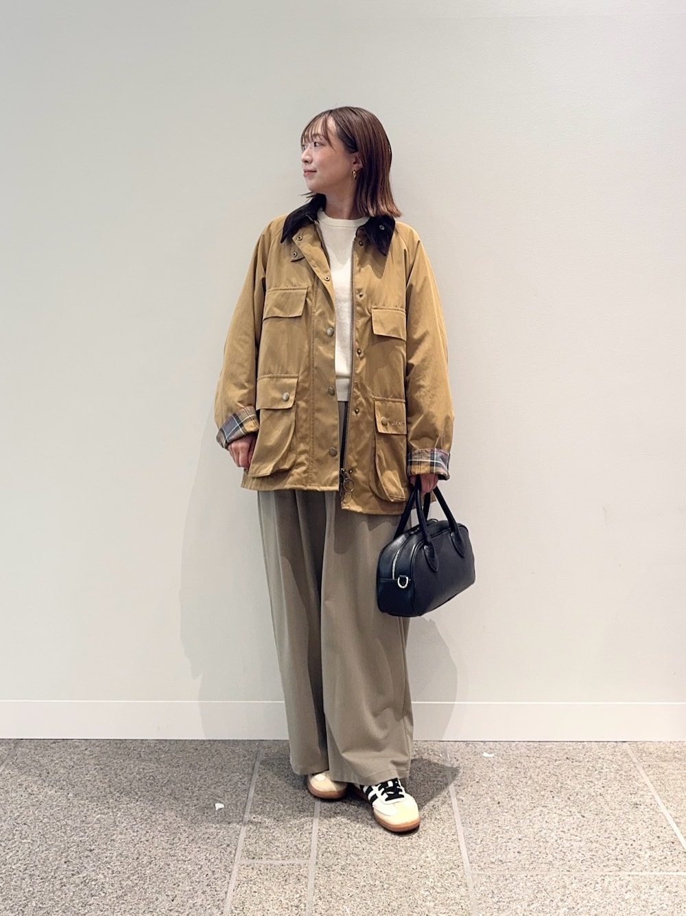 ベージュ系のその他アウター、ブラック系のショルダーバッグ、ベージュ系のスニーカーを着用したレディースの秋コーディネートの1枚目の写真