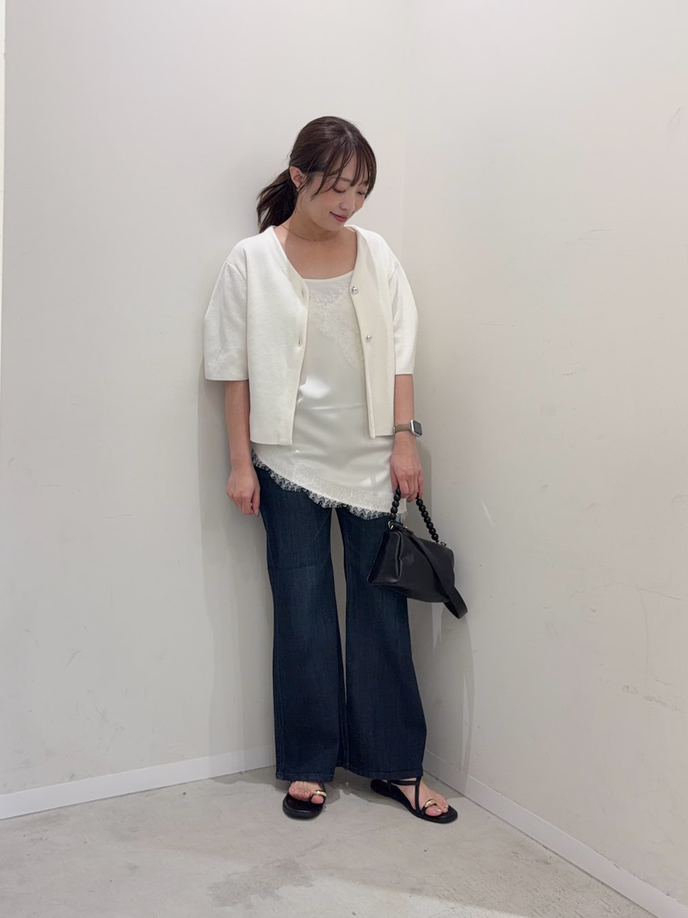 ホワイト系のカーディガン/ボレロ、ホワイト系のキャミソール、ブルー系のデニムパンツを着用したレディースの夏コーディネートの1枚目の写真