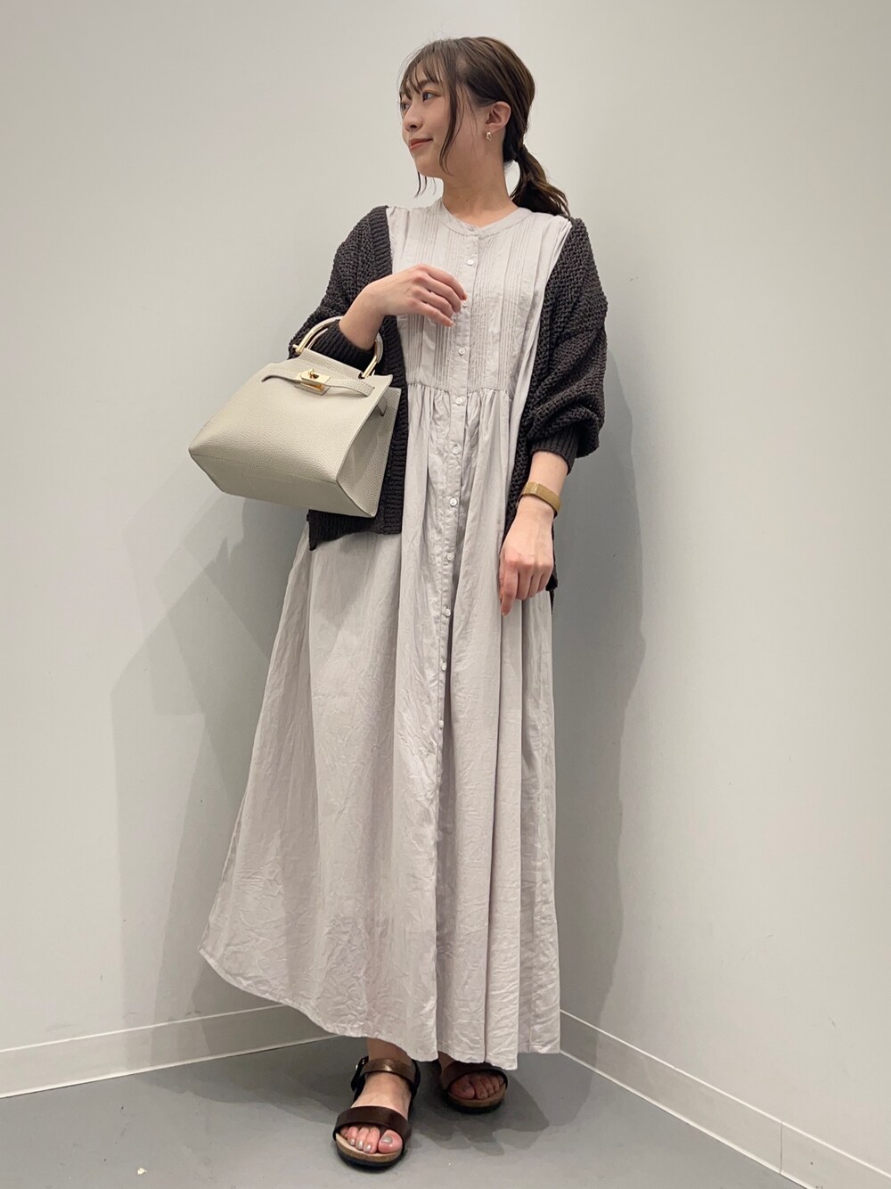 グレー系のワンピース、グレー系のカーディガン/ボレロ、ホワイト系のハンドバッグを着用したレディースの夏コーディネートの1枚目の写真
